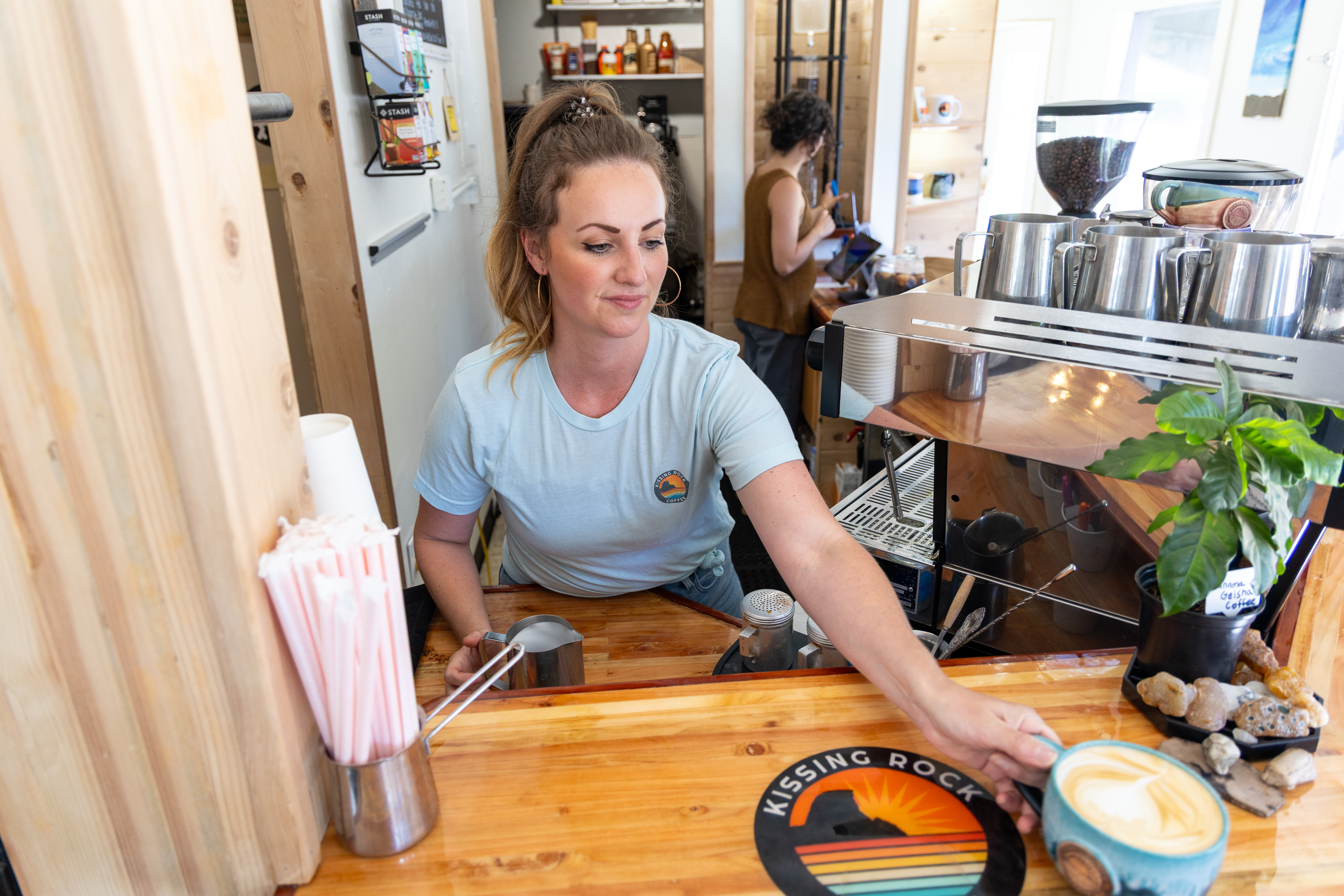 Barista serving a latte at Kissing Rock Coffee in Gold Beach