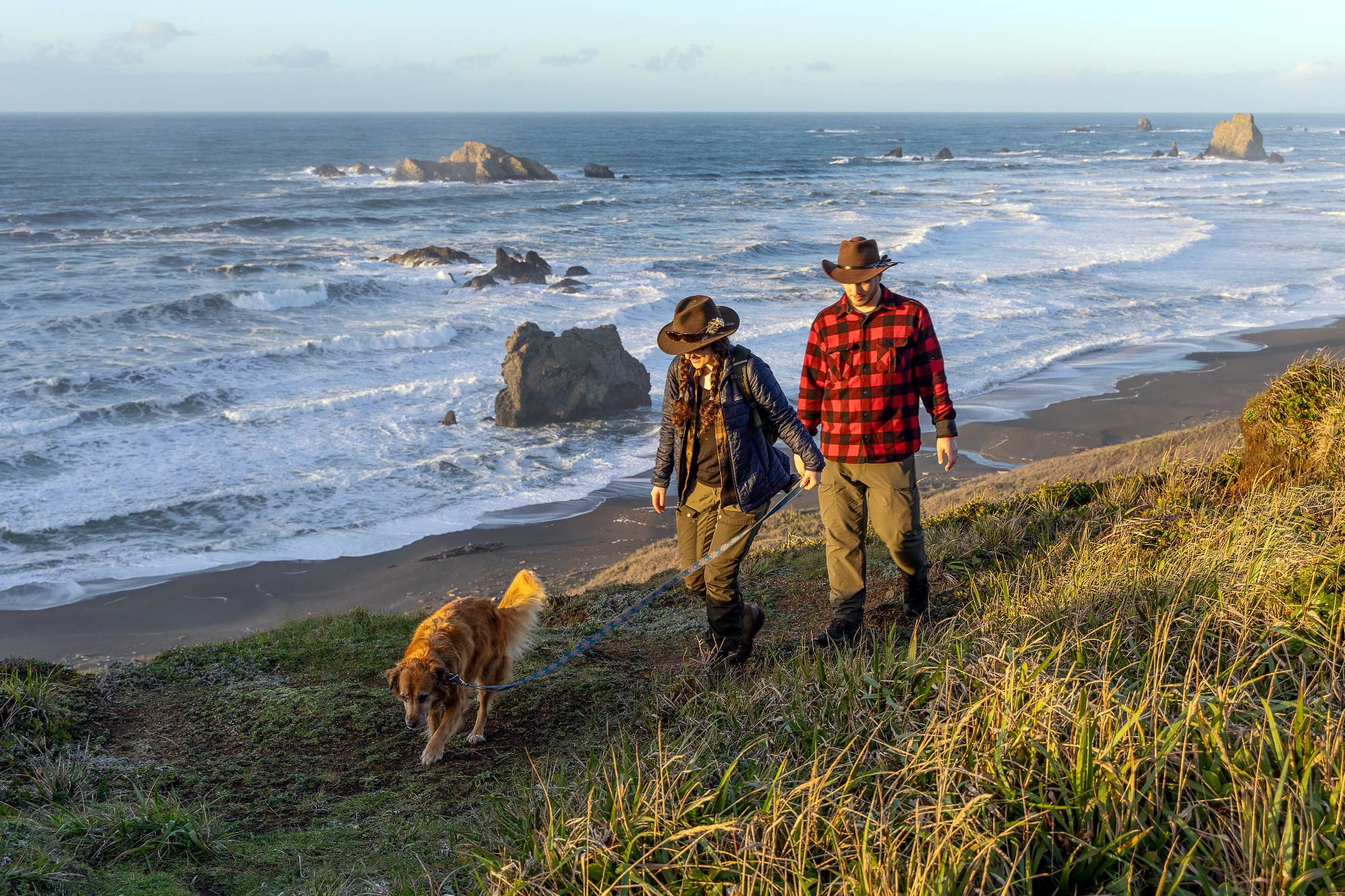 Couple hiking with dog along Cape Blanco coastline